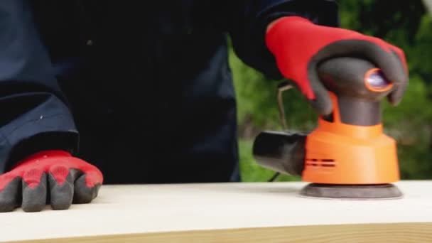 A man polishes wood with a power tool, a close-up. Handmade wood, cleaning wood with sandpaper — Stock Video