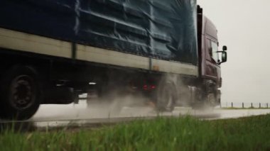 Yarı karavan yarı karavan kargo taşır yağmurlu bir yolda yaz aylarında, yakın çekim. Kaygan yol, taşımacılık endüstrisi. Yavaş çekim
