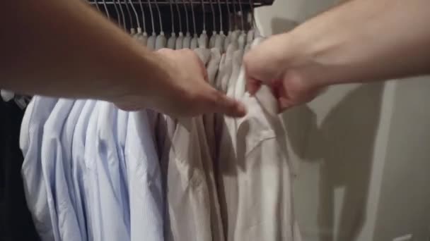 Scegliere vestiti alla moda nel negozio, controllare la qualità del materiale. Concetto di shopping per camicie e magliette, giacche, sfondo — Video Stock