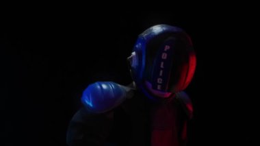 Siberpunk gelecek konsepti. Polis memuru, biyonik sayborg ya da robot karanlıkta fenerli silah doğrultuyor. Halfman kameraya gider ve çerçeveyi bırakır. Bilim kurgu sahnesi, fantezi, bilim. Kırmızı mavi ışık