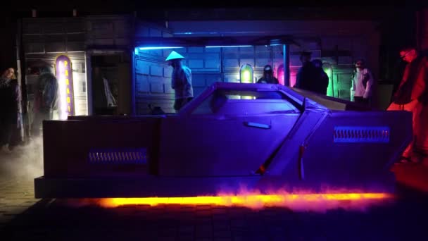 Concepto cyberpunk. Coche futurista está estacionado en la calle por la noche. La gente está hablando entre sí. Iluminación de neón. Escena de ciencia ficción, fantasía, ciencia ficción. Mundo del mañana. El humo viene de debajo del auto. — Vídeo de stock