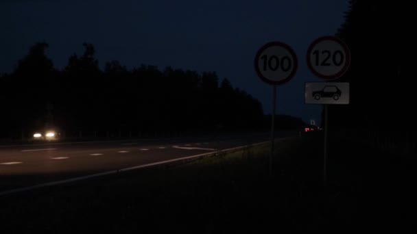 Verkeerstekens van snelheidsbeperking 's nachts op de snelweg. Auto 's rijden op de weg met koplampen aan, verkeersveiligheid. Kopieer ruimte voor tekst — Stockvideo