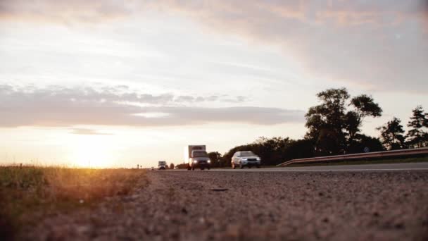 De beweging van een colonne auto 's op een landweg in de avond tegen de achtergrond van een prachtige zonsondergang. Auto 's en vrachtwagens. Kopieer ruimte voor tekst, time-lapse — Stockvideo