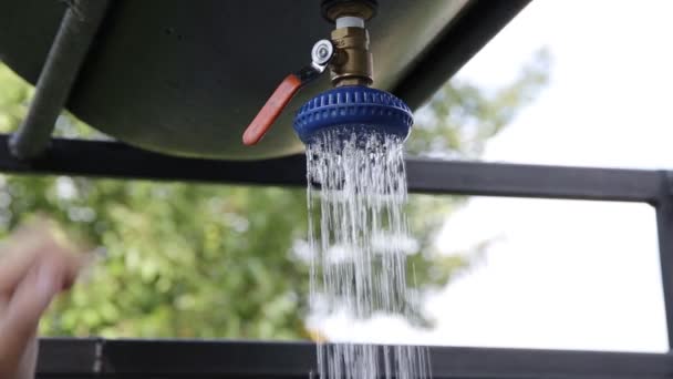 Um homem abre a torneira de um chuveiro de dacha de verão com água fria. Lavagem na natureza, close-up — Vídeo de Stock
