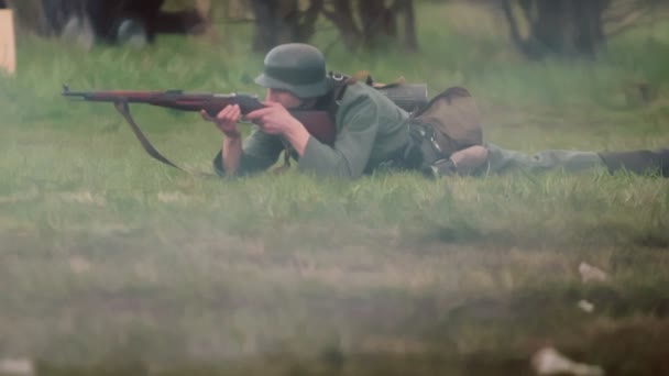 Żołnierz Wehrmachtu w mundurze armii niemieckiej leży i strzela z karabinu podczas rekonstrukcji inwazji na ZSRR 22 czerwca 1941 r. podczas II wojny światowej na froncie wschodnim. Bitwa w zwolnionym tempie — Wideo stockowe