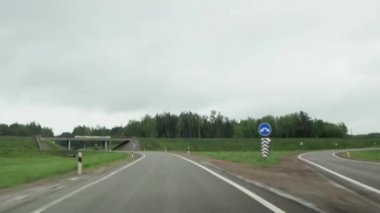 Araba arka planda, yağmurlu havada asfalt bir köy yolunda sürüyor. Zaman Uygulaması