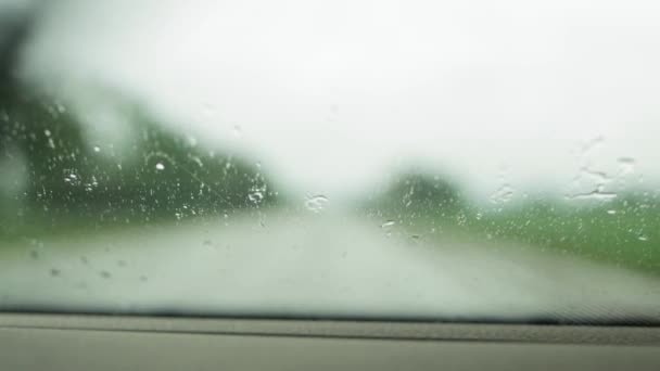 背景には、フロントガラスワイパーで洗浄されている湿式フロントガラスの車の窓からの眺め。テキスト、可視性のためのコピースペース — ストック動画