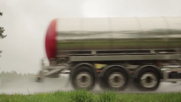 Petrol ürünleri taşımak için kullanılan tanker kamyonları yazın yağmur ve bulutlu havada farları açık olarak otoyola çıkıyorlar. Benzin taşıma konsepti, tehlikeli kargo. Yavaş çekim — Stok video