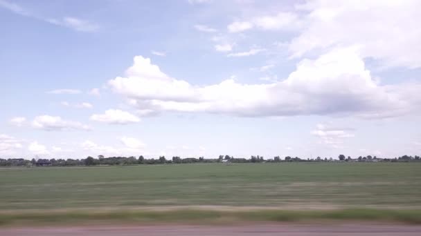 車の窓からの景色は、フィールドや牧草地に。雲と青空を背景に美しい自然。旅、テキストのためのコピースペース — ストック動画