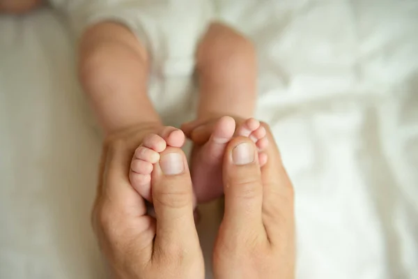 Baba, bebeğin bacaklarını tutuyor. Papa 'nın ellerinde yeni doğan bir bebek.. 
