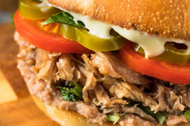 Ev yapımı Meksika Pork Torta Sandviçi, yanında fasulye ve domates.