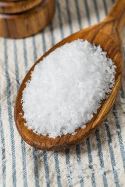 Tahta kaşıkta çiğ, beyaz, pullu deniz tuzu.