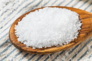 Tahta kaşıkta çiğ, beyaz, pullu deniz tuzu.