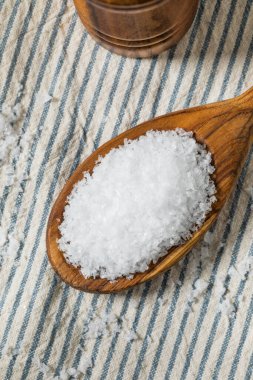 Tahta kaşıkta çiğ, beyaz, pullu deniz tuzu.