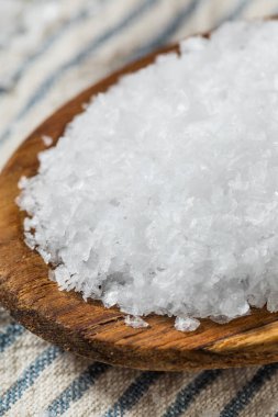 Tahta kaşıkta çiğ, beyaz, pullu deniz tuzu.