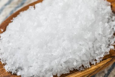 Tahta kaşıkta çiğ, beyaz, pullu deniz tuzu.