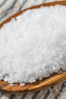 Tahta kaşıkta çiğ, beyaz, pullu deniz tuzu.