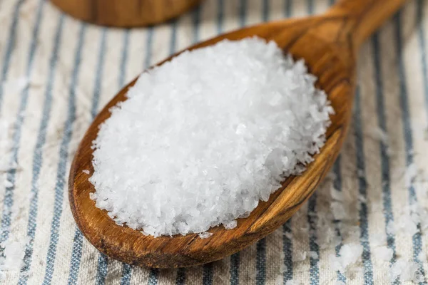 Tahta kaşıkta çiğ, beyaz, pullu deniz tuzu.