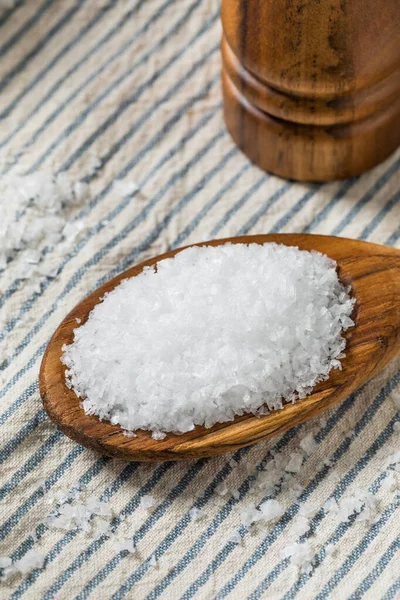 Tahta kaşıkta çiğ, beyaz, pullu deniz tuzu.