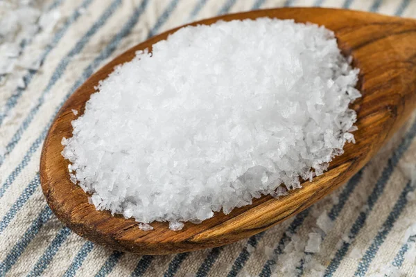 Tahta kaşıkta çiğ, beyaz, pullu deniz tuzu.