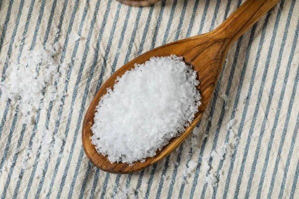 Tahta kaşıkta çiğ, beyaz, pullu deniz tuzu.