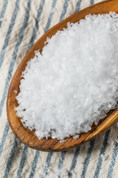 Tahta kaşıkta çiğ, beyaz, pullu deniz tuzu.