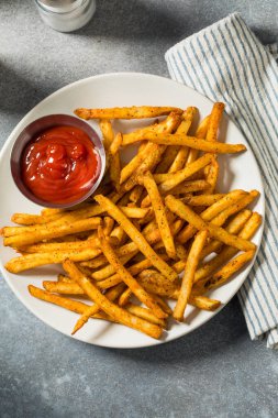 Ev yapımı baharatlı patates kızartması ve ketçaplı tabak.