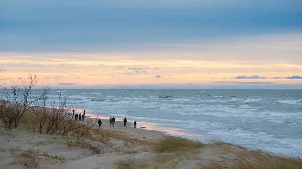 İnsanlar kış akşamları Palanga 'da sahilde yürüyorlar.