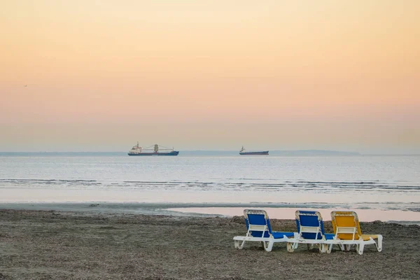 Kumsalda üç güneşli yatak ve Larnaka 'da gemiler.