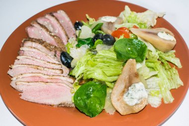 Kızarmış ördek dilimleri ve salata ve armut.