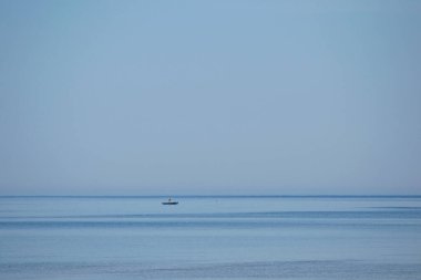 Ufuktaki sakin ve boş denizde küçük bir balıkçı teknesi
