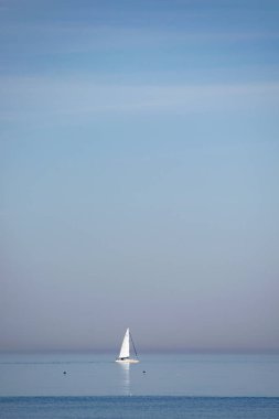 Ufuktaki sakin ve boş denizde yelkenli.