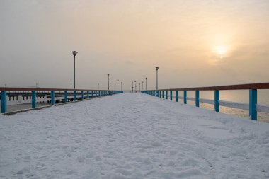 Kışın kar ve bulutların altında güneşle kaplı Palanga Köprüsü