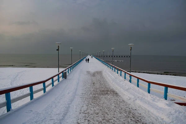 Palanga Köprüsü, kara kış gününde insanlarla ve kara bulutlarla