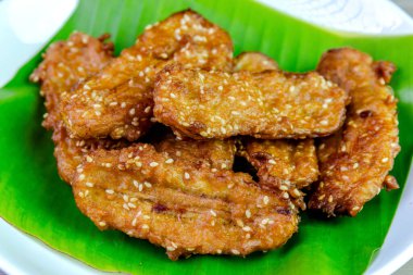 Beyaz bir tabakta muz yaprağında servis edilen kızarmış Tayland muzu, tatlı ve çıtır çıtır dokulu geleneksel Asya atıştırmalığıdır. Üst görünüm yakın çekim