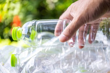 Plastik atık, boş bir plastik şişeyi tutan, plastik atık sorununu sembolize eden, atık yönetimi çabaları ve plastik atıkların azaltılmasına yönelik farkındalık