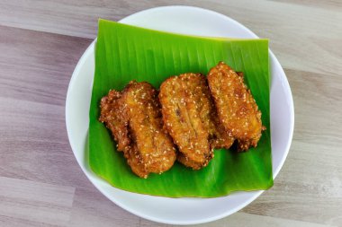 Beyaz bir tabakta muz yaprağında servis edilen kızarmış Tayland muzu, tatlı ve çıtır çıtır dokulu geleneksel Asya atıştırmalığıdır. Üst görüntü görüntüsü