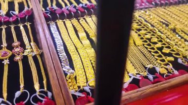 Altın mücevherler, altın bilezikler ve mücevher mağazası vitrininde sergilenen kolyeler zenginliği, yatırımı ve lüksü simgeliyor. Finansal, ekonomik veya altın piyasası kavramları için mükemmel