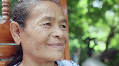 Elderly woman face Happy and Smiled slightly, Portrait elder with facial expression, Close-up portrait grandmother smiling happily on nature garden background, Thai asian