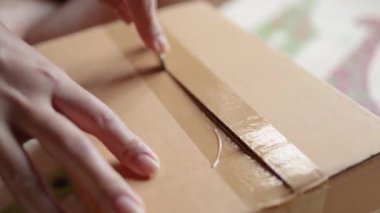 Eller dikkatlice bir karton paket kutusunu açıyor, paketleri açıyor, çevrimiçi alışveriş, teslimat veya paket açma kavramını temsil ediyor