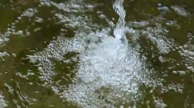 Bir gölete dökülen su tazeliği, saflığı ve doğal hareketi temsil eden birçok hava kabarcığı yaratır.