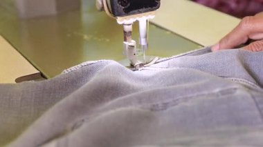 Dikiş makinesiyle kot kumaşı dikmek, yakın çekim, ayrıntılı işçilik ve giysi üretim işi