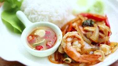 Baharatlı kızarmış deniz ürünleri ve büyük karidesler, yakın plan, acılı balık sosuyla servis ediliyor. Lezzetli ve iştah açıcı bir Tayland ev yemeği.