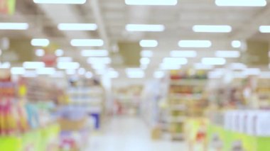 Parlak ışık ve yumuşak odaklı raflarla kaplı bulanık bir süpermarket iç mekanı, perakende atmosfer ve alışveriş ortamı aktarımı