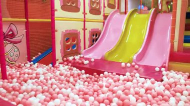 Pembe ve beyaz top havuzlu kapalı oyun alanı slaytları aile, çocuklar ve eğlence için ideal, parlak ve eğlenceli bir atmosfer yaratıyor.