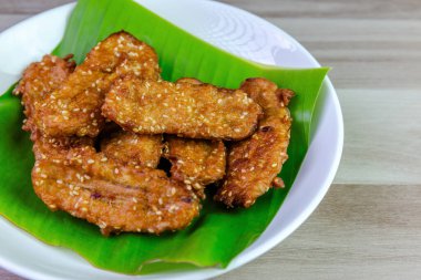 Beyaz bir tabakta muz yaprağında servis edilen kızarmış Tayland muzu, tatlı ve çıtır çıtır dokulu geleneksel Asya atıştırmalığıdır. Üst görünüm yakın çekim, boşluk kopyala