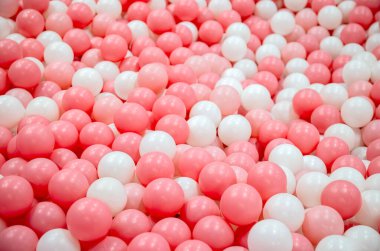 Oyuncak top, pembe ve beyaz top yoğun bir şekilde top havuzunu dolduruyor, top havuzunda plastik top, çocuk teması ve eğlence için parlak, neşeli, neşeli bir ortam yaratıyor.