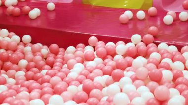 Oyuncak top, pembe ve beyaz top yoğun bir şekilde top havuzunu dolduruyor, top havuzunda plastik top, çocuk teması ve eğlence için parlak, neşeli, neşeli bir ortam yaratıyor.