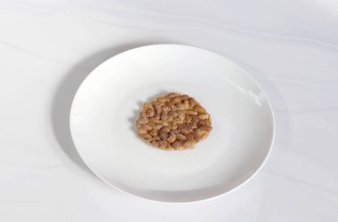 Fıstık ezmesi, az ışık alan beyaz bir tabağa konur. Yemek, tatlı ve geleneksel içerik için uygundur.