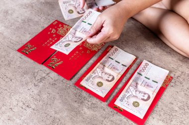 Ay Yeni Yılı Kutsamaları için Tayland banknotları ile Kırmızı Zarflar 'a angpao vermek, Çin Yeni Yılı için banknotları kırmızı zarflara yerleştirmek. Angpao şans, refah ve zenginlik için verir.